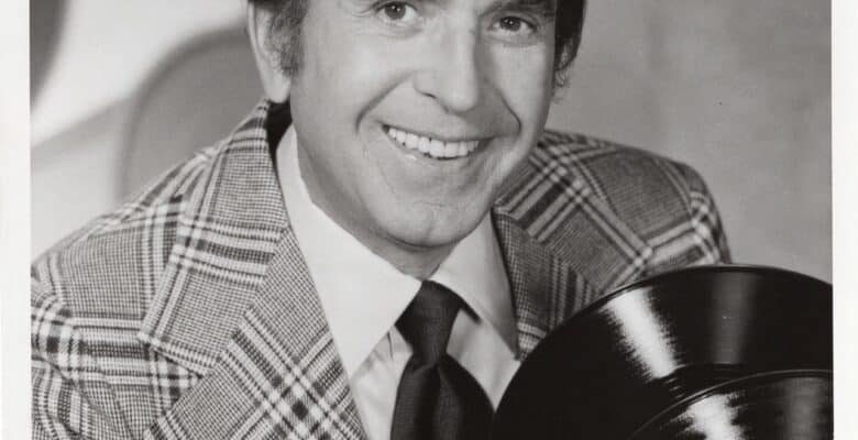 Portrait of Dennis James holding a record in black and white