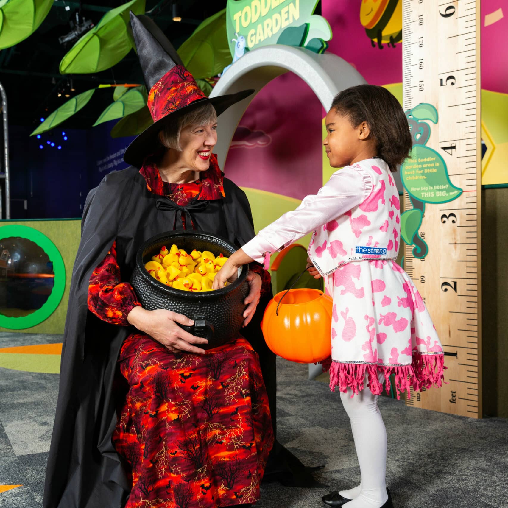 Girl trick-or-treating with a woman dressed as a witch
